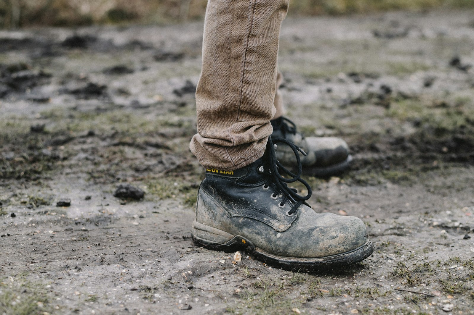 Muddy work boots standing on wet ground